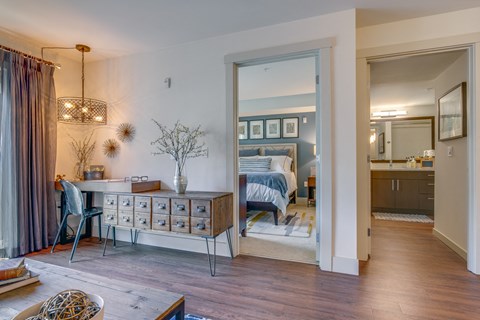 a living room with a bedroom in the background and a dining room table and chairs